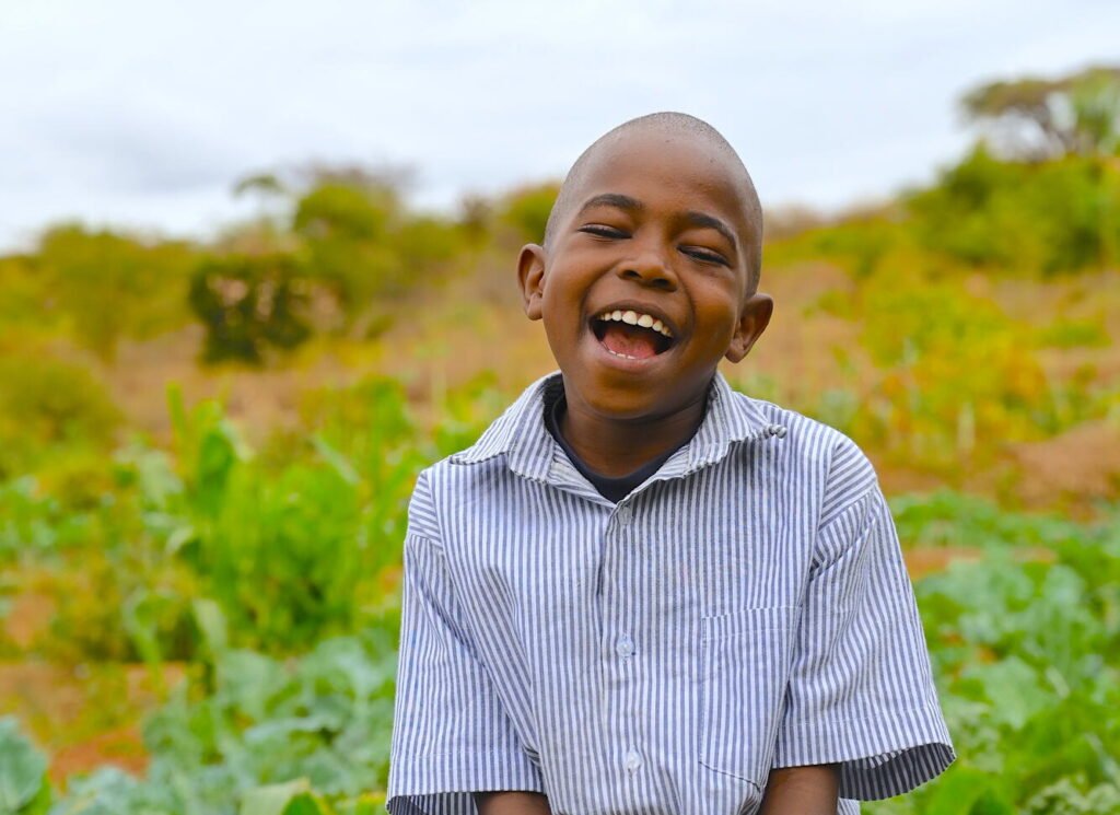 Kenialainen Joshua hymyilee leveästi kameralle pellon edessä