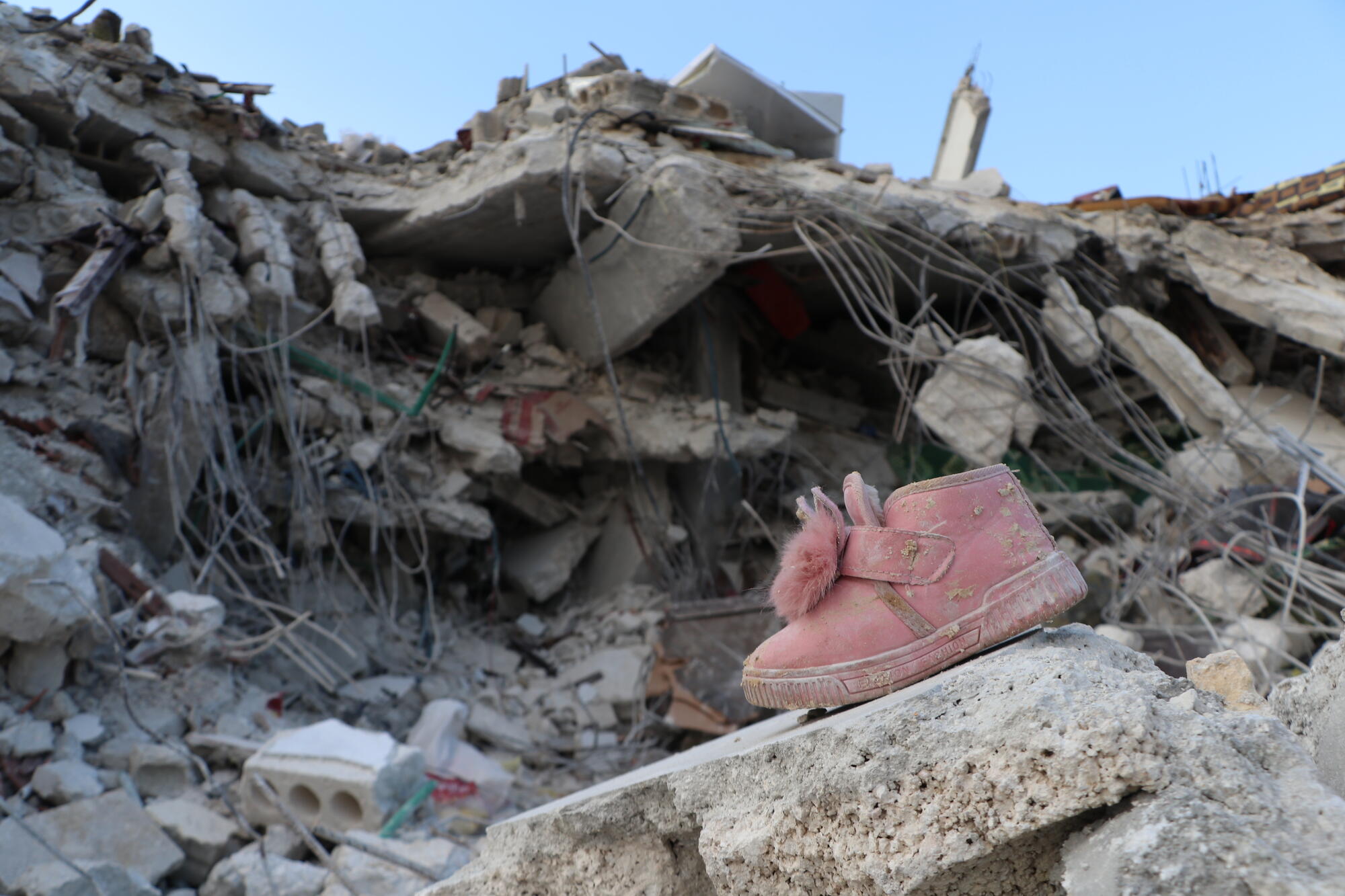 Lapsen kenkä kuvattuna raunioiden edessä Syyriassa.