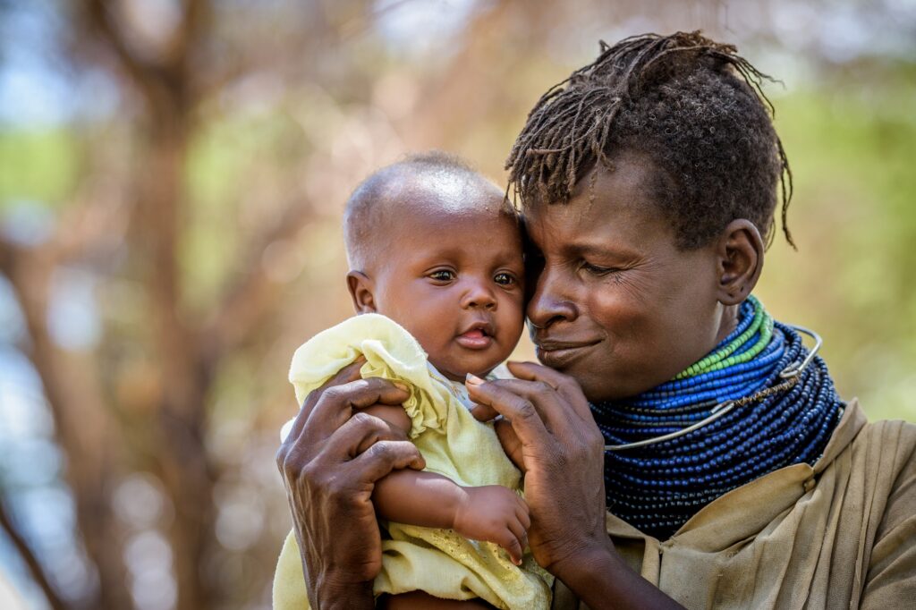 Kenialainen äiti halailee vauvansa ja hymyilee.