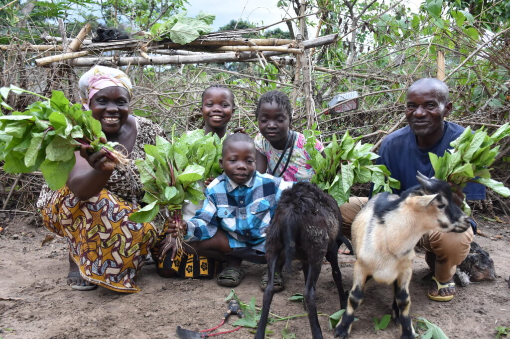 Marie ja hänen perheensä esittelevät kasvimaansa satoa. Perhe saivat World Visionilta koulutusta viljelemisestä sekä taloudellista tukea kasvimaahan perustamiseen.