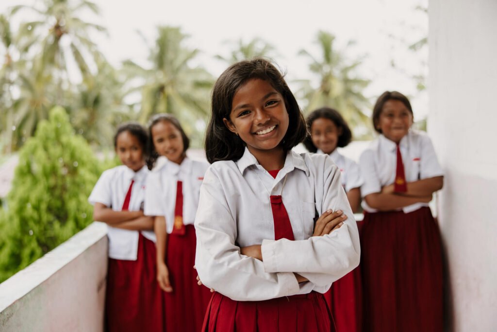 Indonesialainen tyttö hymyilee itsevarmasti kameralle. Taustalla näkyy neljä muuta tyttöä.