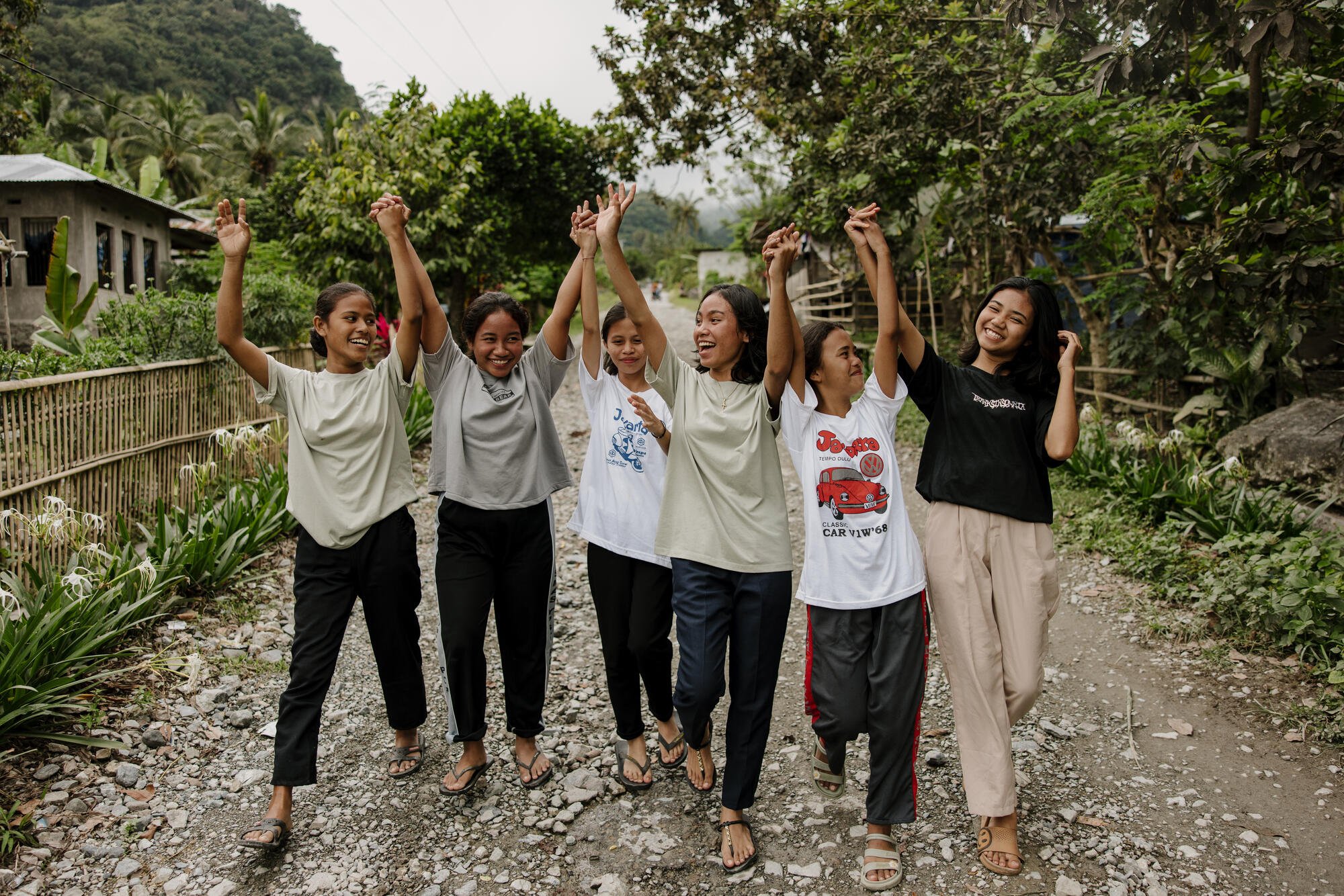 Kuusi indonesialaista tyttöä kävelevät nauraen kohti kameraa, kädet ilmassa, katsomassa toisiaan.