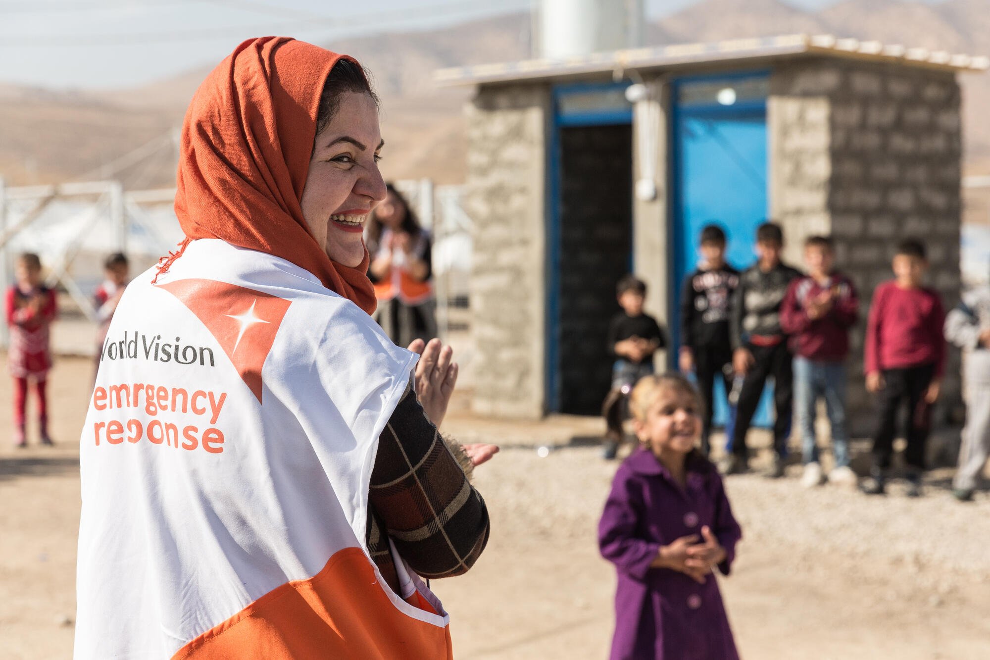 World Vision Irakin paikallinen työntekijä nauraa lasten kanssa.
