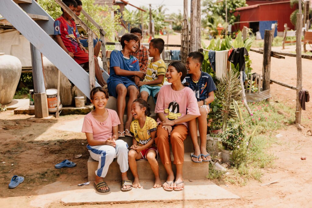 Kambodzalaisia lapsia istuvat portailla nauramassa yhdessä.