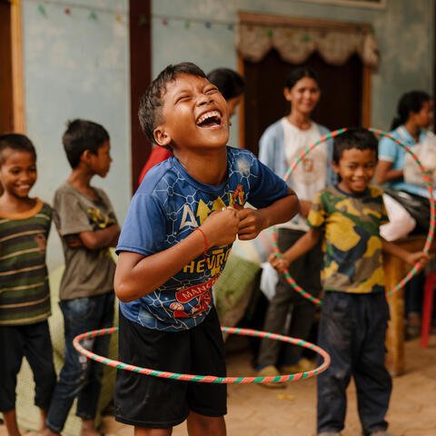 Kambodzalainen poika leikkii nauraen hulahula-vanteella.