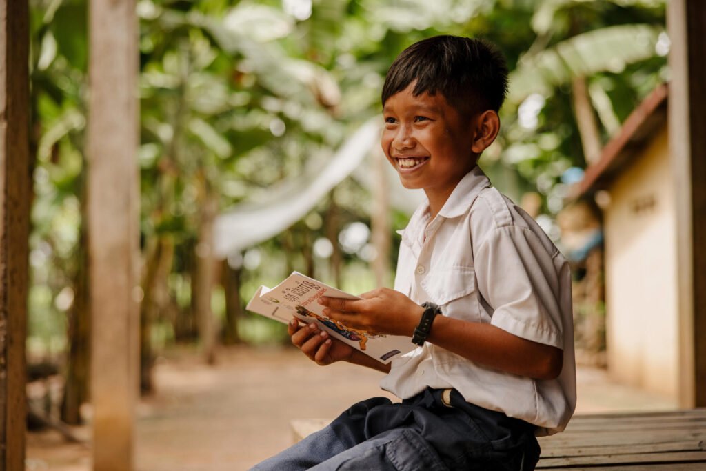 Kambodzalainen poika lukee lehteä ja nauraa.