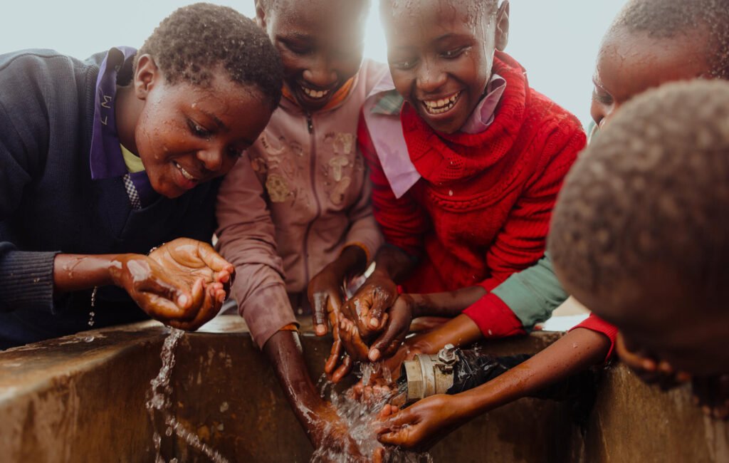 Kenialaisia lapsia pesemässä kädet ja juomassa uudesta vesipisteestä.