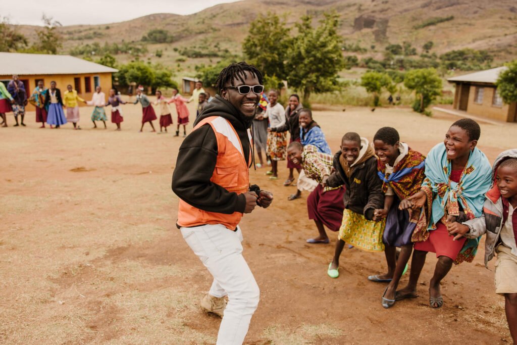 World Vision Malawin työntekijö tanssimassa lasten kanssa.