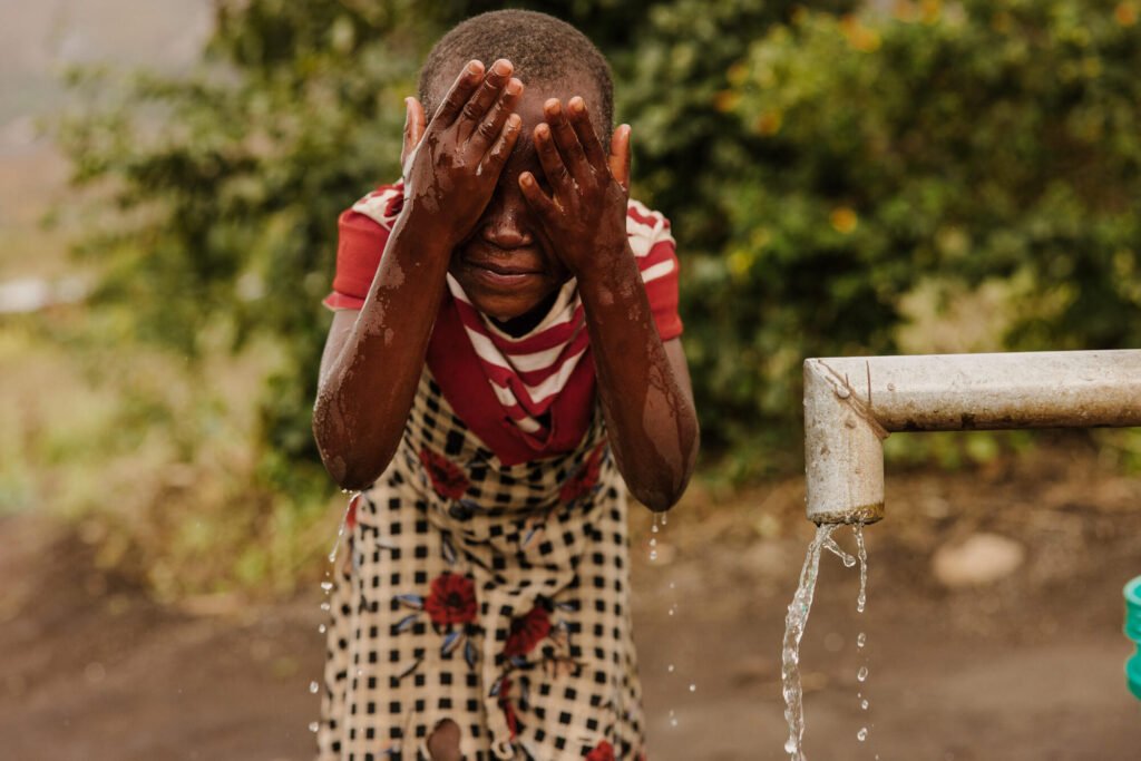 Malawilainen tyttö pesee kasvojaan puhtaalla vedellä vesipisteellä.