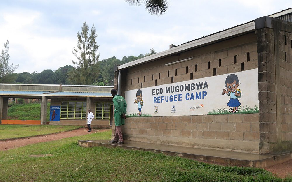 Kaksi työntekijää seisovat Mugombwan Early Childhood Development -koulun edessä.