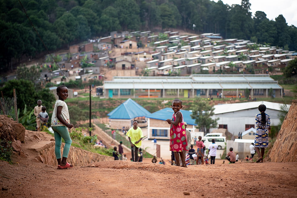 Ruandalaisia lapsia hymyilemässä kameralle. Taustalla näkyy Mugombwan pakolaisleiri.
