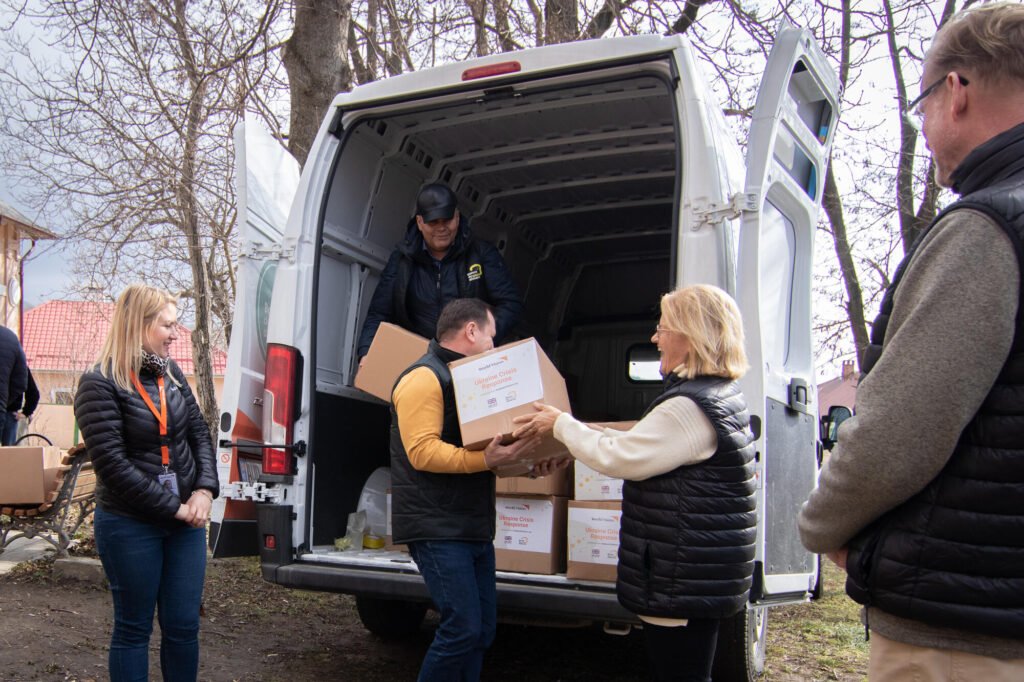 World Vision Moldovan työntekijät kantavat hätäaputarvikelaatikkoja pakusta.