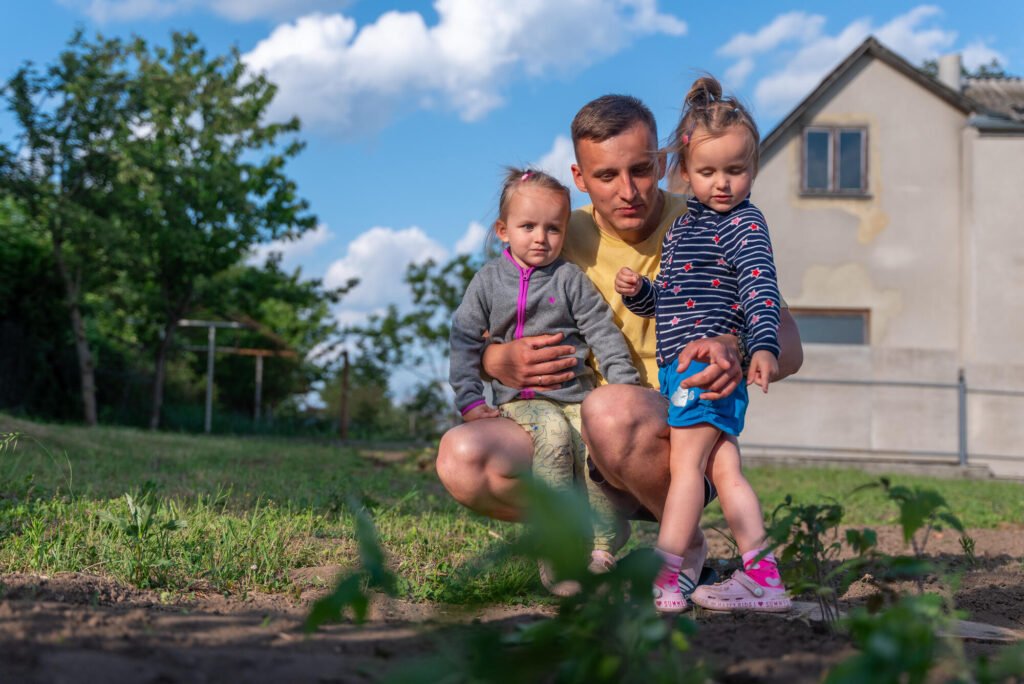 Volodymyr tyttäriensä kanssa katsomassa perheen kasvimaata.
