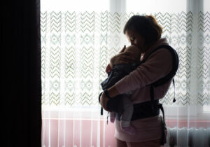 Ukrainalainen äiti seisoo ikkunan edessä ja pitää vauvansa sylissään.