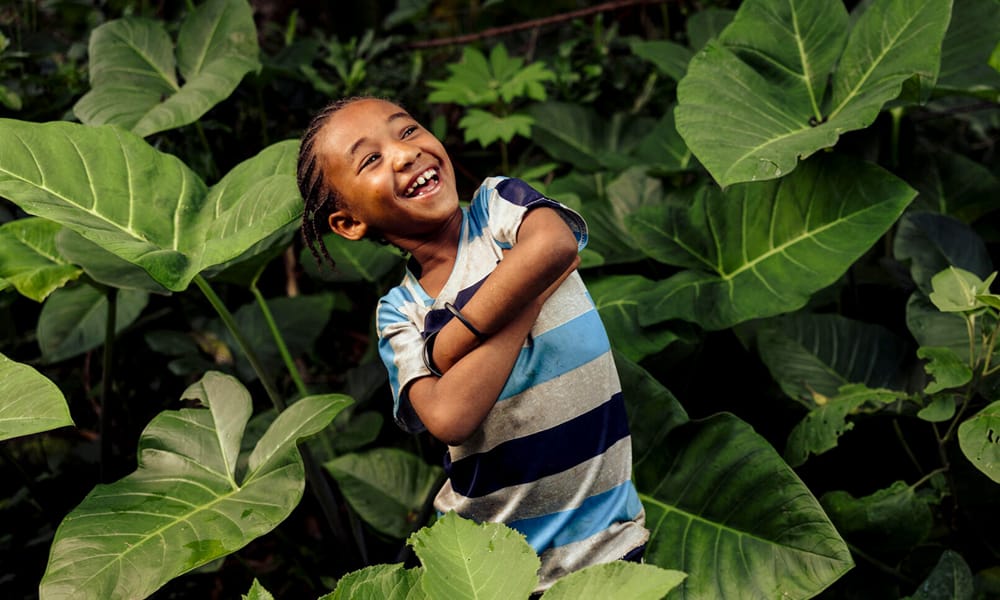 Etiopialainen lapsi hymyilee keskellä luontoa.