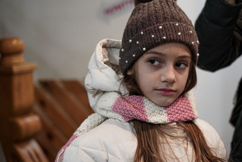 Talvivaatteisiin pukeutunut ukrainalainen tyttö Veronika, 8, lämmittelee World Visionin tukemassa lapsiystävällisessä tilassa Kiovassa.