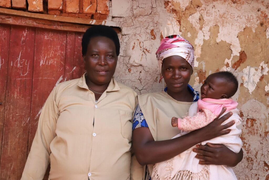 Ravitsemusryhmän vetäjät Mary Chantal ja Divine seisovat vierekkäin ja katsovat kameraan. Divinellä on sylissä Evimika-vauva,