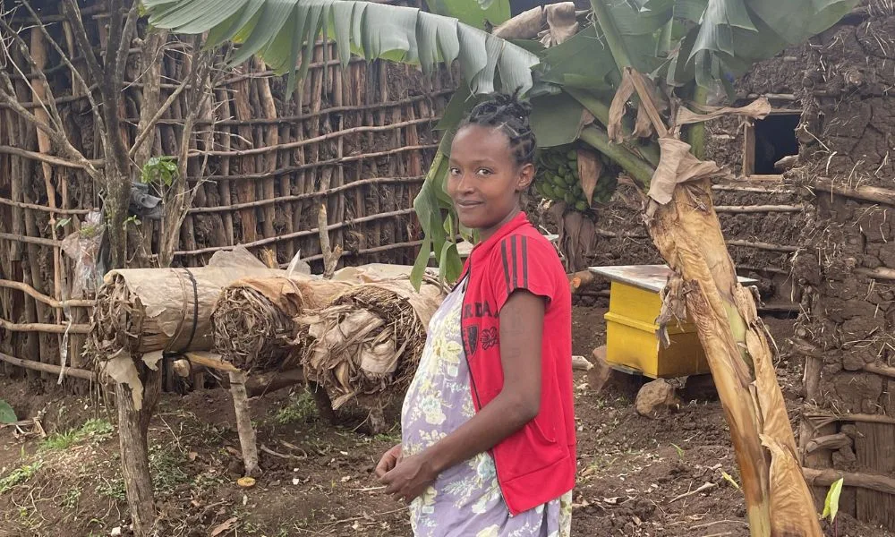 Etiopialainen yrittäjänainen Betelhem seisoo mehiläistarhansa edessä ja hymyilee.