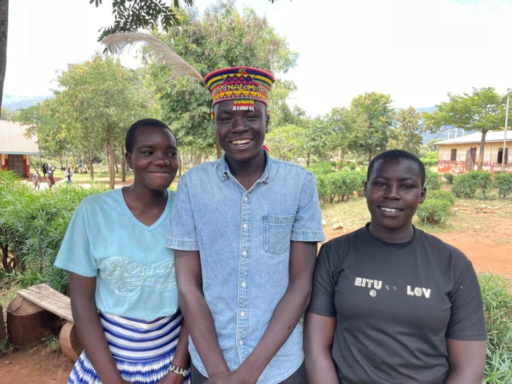 Kolme kenialaista nuorta katsoo hymyillen kameraan