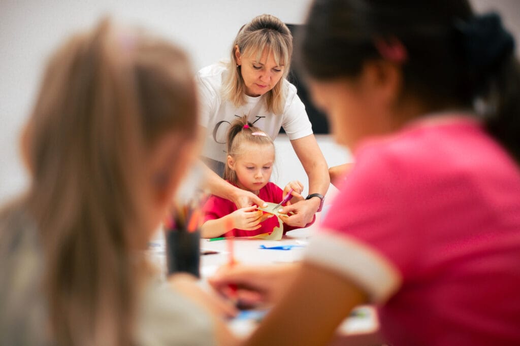 Ukrainalaisia lapsia ja opettaja koulussa askartelemassa