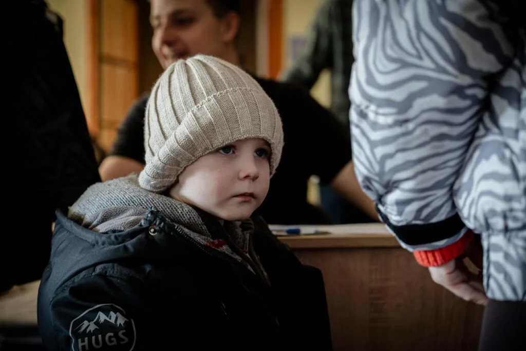 Vakavan näköinen ukrainalainen pikkupoika pipossa ja talvitakissa.