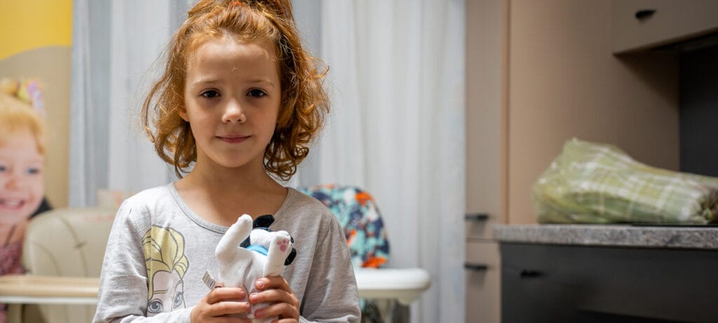 Ukrainalainen punahiuksinen tyttö esittää pehmolelukoiransa kameralle.